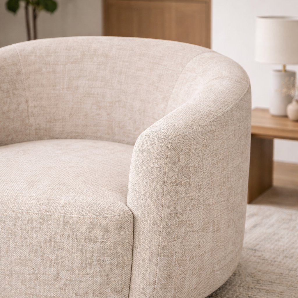 Beige armchair in a living room setting with a lamp and plant in the background.